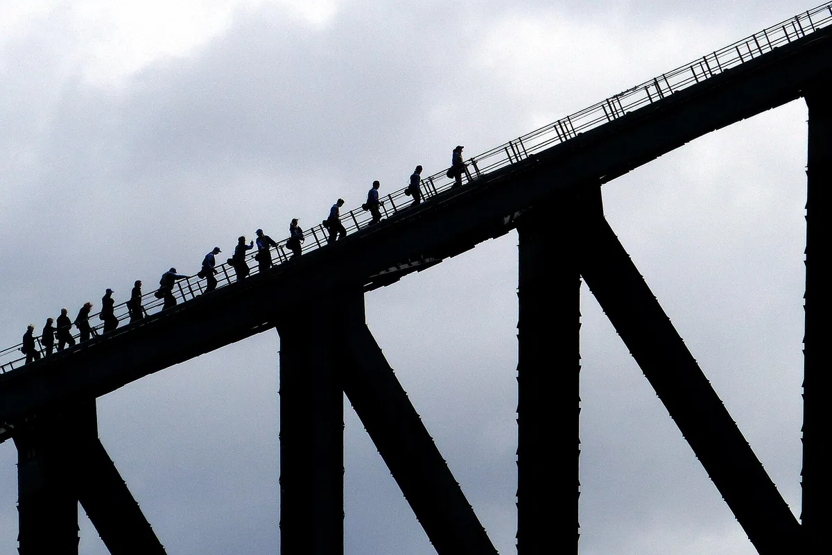 Harnessed climbers ascending the arch of Sydney Harbour Bridge